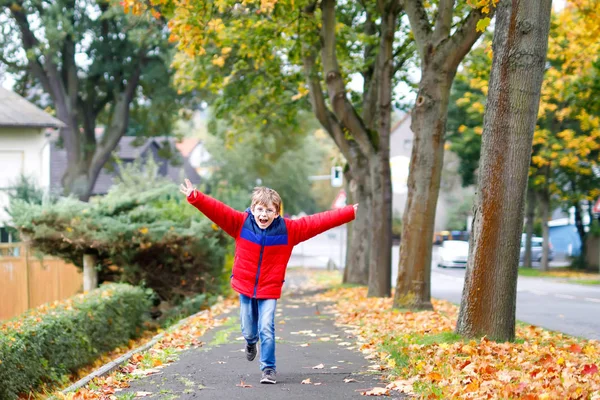 Happy little boy running on autumnal street after school. — Stock Photo, Image