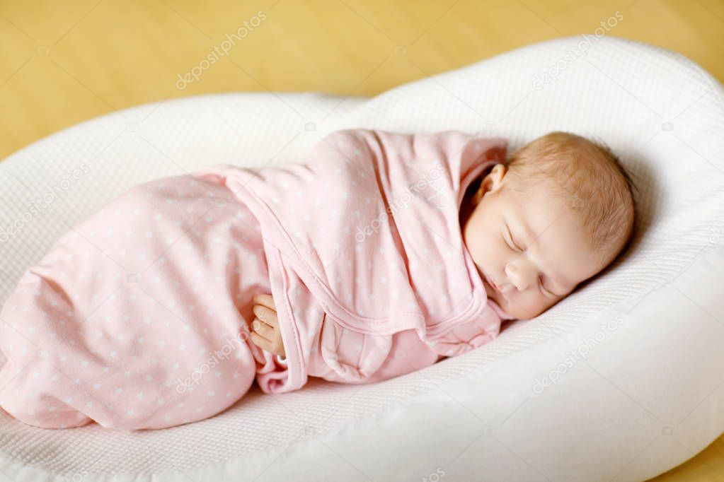 One week old newborn baby girl sleeping wrapped in blanket