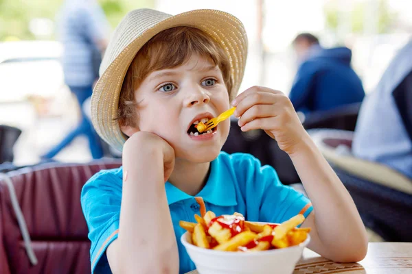 Cute healthy preschool kid boy eats french fries potatoes with ketchup — Stock Photo, Image