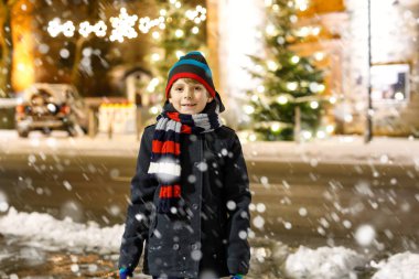 Mutlu çocuk kışın karla eğleniyor.