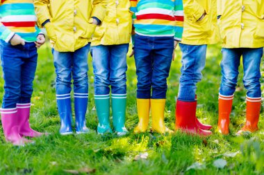 Küçük çocuklar, oğlanlar ve kızlar renkli yağmur botları. Çocuklarda farklı lastik çizme, kot pantolon ve ceket close-up. Yağmurlu sonbahar Ayakkabı