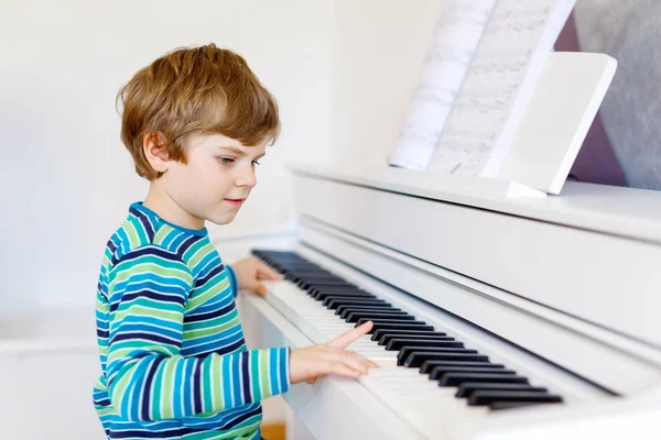 Bonito menino saudável tocando piano na sala de estar ou escola de música. Criança pré-escolar se divertindo com a aprendizagem de tocar instrumento de música. Educação, conceito de competências — Fotografia de Stock