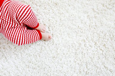 Kırmızı Noel Baba pantolonlu bebek bedeni ve bacaklarının yakın çekimi. Yeni doğan çocuk, küçük kız ya da erkek. Çocuk eğleniyor. Aile, yeni hayat, çocukluk, tatil konsepti. Noel kartpostalı için kapanış: