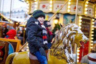 Sevimli küçük çocuk çocuk üstünde neşeli gitmek yuvarlak atlıkarınca hayvan Noel lunapark veya market, açık havada, At Binme. Mutlu çocuk eğleniyor geleneksel aile xmas pazarında, Berlin, Almanya