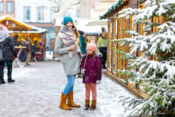 Mała dziewczynka cute i młoda matka zabawy na tradycyjnym niemieckim rynku Bożego Narodzenia podczas silnych opadów śniegu. Szczęśliwe dziecko i piękna kobieta korzystających z rynku rodzinnego w Niemczech, Drezno — Zdjęcie stockowe