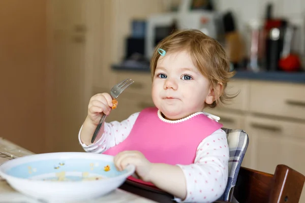 Schattig meisje dat eet van puree en puree. voedsel, kind, voeding en ontwikkeling concept -schattige peuter, dochter met lepel zitten in de kinderstoel en leren eten door zelf. — Stockfoto