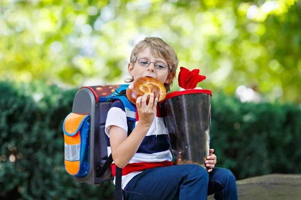 学校への彼の最初の日に眼鏡やバックパックやサッチェルを持つ幸せな小さな男の子。子供の屋外で暖かい晴れた日には、学校のコンセプトに戻る。子供とともに伝統的な通学路-ドイツ語. — ストック写真