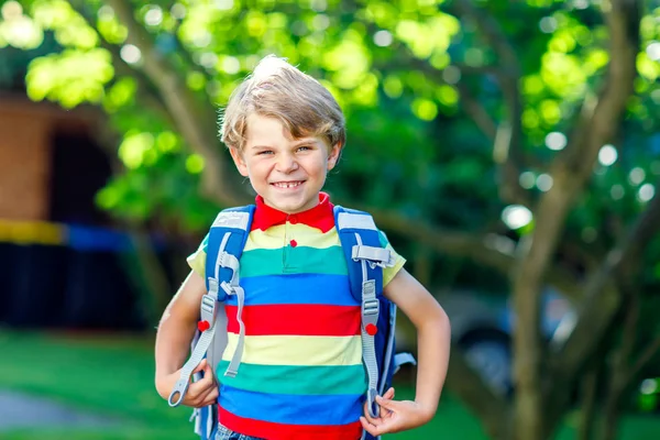 Glücklicher kleiner Junge mit Brille und Rucksack oder Schulranzen an seinem ersten Schul- oder Kindergartentag. Kind an warmen, sonnigen Tagen im Freien, Zurück zum Schulkonzept. — Stockfoto