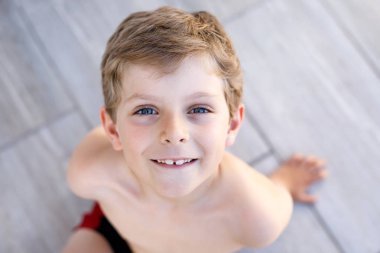 Güneşli yaz gününde gülümseyen güzel çocuk portresi. Mutlu çocuk kameraya bakıyor. Sarı saçlı ve mavi gözlü sevimli bir çocuk.