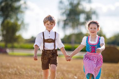 İki çocuk, erkek ve kız ile saman balya buğday alanında geleneksel Bavyera kostümleri