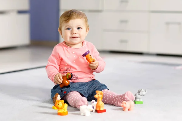 Adorable baby girl playing with domestic toy pets like cow, horse, sheep, dog and wild animals like giraffe, elephant and monkey. Happy healthy child having fun with colorful different toys at home — Stock Photo, Image