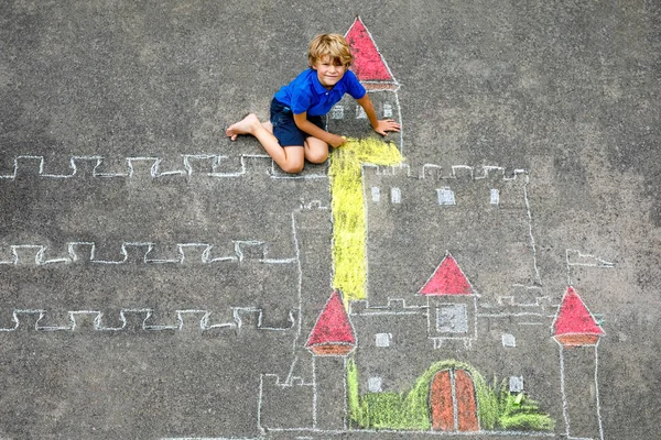 Маленький мальчик рисует рыцарский замок и крепость с разноцветными мелом. Счастливый дошкольник, получающий удовольствие от создания картинки с шалфеем. Творческий отдых для детей и детей летом — стоковое фото