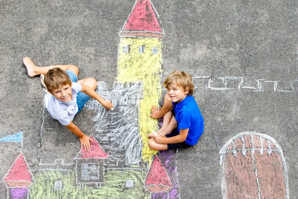 Zwei kleine Jungen zeichnen eine Ritterburg mit bunten Kreiden auf Asphalt. glückliche Geschwister und Freunde, die Spaß am Kreidebild und am Malen haben. Kreative Freizeit für Kinder im Sommer. — Stockfoto