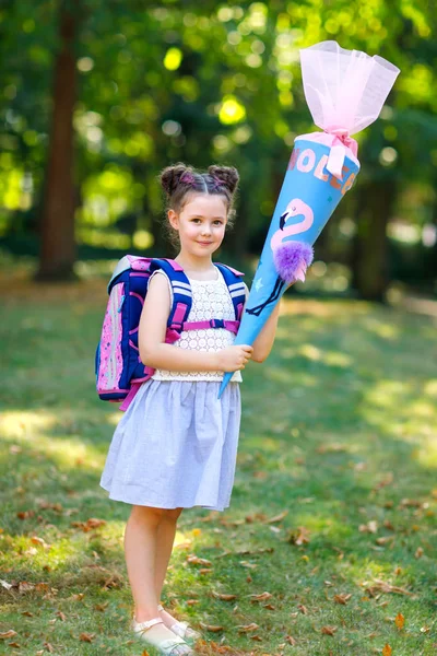 Šťastné dítě holčička s batoh nebo brašnu a velký školní batoh nebo kužel tradiční v Německu za první den ve škole. Zdravý rozkošný dítě venku, v parku. — Stock fotografie