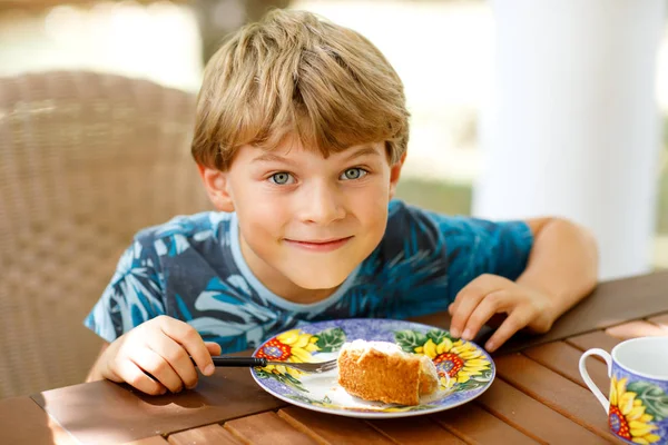 Schöner kleiner Junge, der im Urlaub im Restaurant Apfelkuchen isst. glückliches gesundes Kind im Sommer in einem Café im Freien, Kuchen essen — Stockfoto