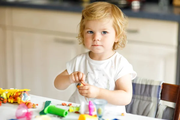Αξιολάτρευτο χαριτωμένο κοριτσάκι με πολύχρωμο πηλό. Υγιές μωρό παίζει και τη δημιουργία παιχνιδιών από τη ζύμη παιχνίδι. Μικρό παιδί σχηματοποίηση πηλό μοντελοποίησης και μάθηση — Φωτογραφία Αρχείου