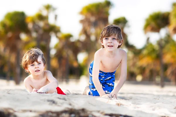 Dwa małe dzieci Chłopcy świetnie się bawią na tropikalnej plaży, szczęśliwy, przyjaciele, grając z piasku, pojęcie przyjaźni. Rodzeństwo brothes w spodnie pływać. Key Biscayne, Miami, Floryda — Zdjęcie stockowe