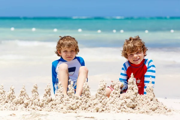 Due bambini ragazzi costruiscono castello di sabbia sulla spiaggia tropicale di Playa del Carmen, Messico — Foto Stock