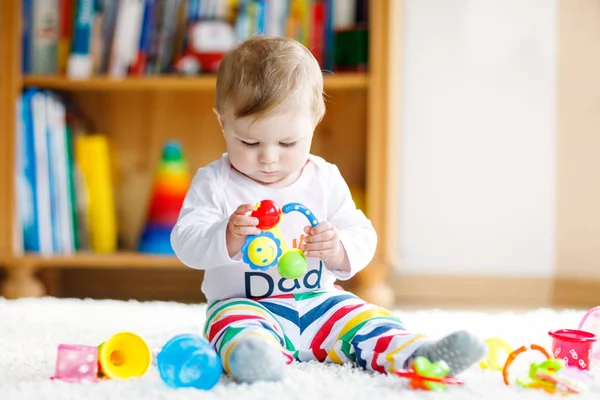 Adorable baby girl playing with educational toys in nursery. Happy healthy child having fun with colorful different toys at home. Baby development and first steps, learning to play and to grab. — Stock Photo, Image