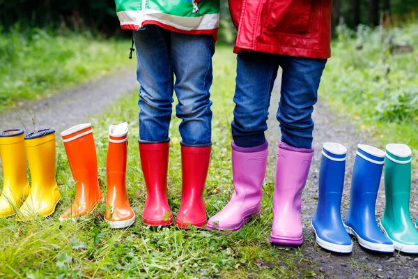 Crianças, meninos e meninas com botas coloridas de chuva. Crianças em pé na floresta de outono. Close-up de alunos e botas de borracha diferentes. Calçado e moda para queda chuvosa — Fotografia de Stock