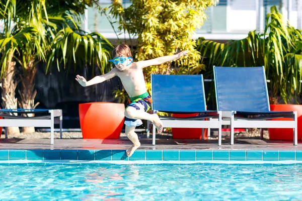 Gelukkig preschool kid jongetje springen in het water bij pool. Kind met plezier in een zwembad. Actieve gelukkig kind winnen. sport, actieve recreatie voor kinderen. — Stockfoto
