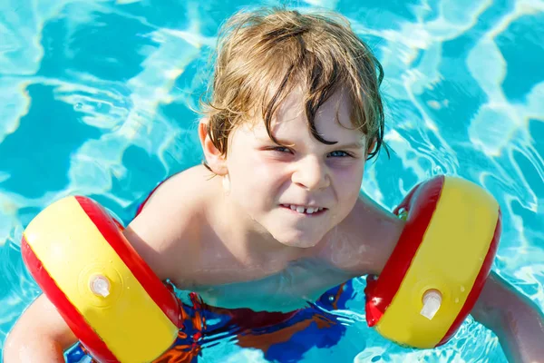 Šťastné dítě chlapec baví v plaveckém bazénu. Aktivní šťastné dítě naučit se plavat. s bezpečnou floaties nebo swimmies. Rodina, dovolená, letní koncepce — Stock fotografie