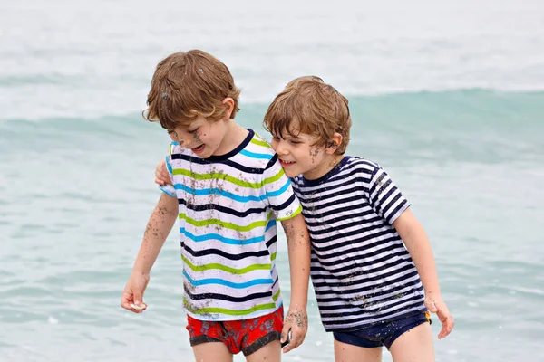 Zwei glückliche kleine Jungen, die am Strand des Ozeans laufen. Lustige Kinder, Geschwister, Zwillinge und beste Freunde machen Urlaub und genießen den Sommer an stürmischen Regentagen. miami, florida Familienporträt. — Stockfoto