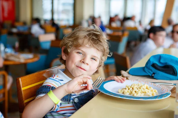 Cute healthy preschool kid boy eats pasta noodles sitting in school or nursery cafe. Happy child eating healthy organic and vegan food in restaurant. Childhood, health concept. — Stock Photo, Image