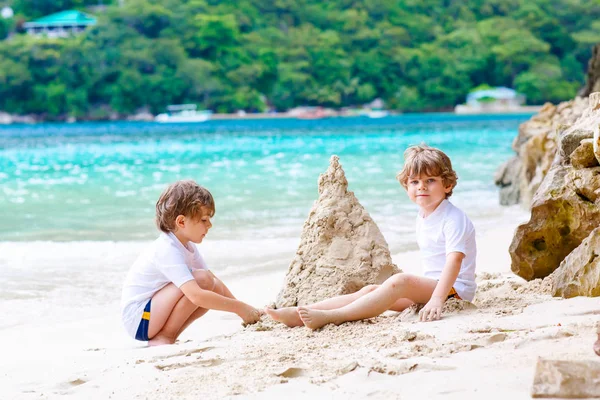 Due bambini piccoli ragazzi si divertono con la costruzione di un castello di sabbia sulla spiaggia tropicale delle Seychelles. bambini che giocano insieme durante le loro vacanze — Foto Stock
