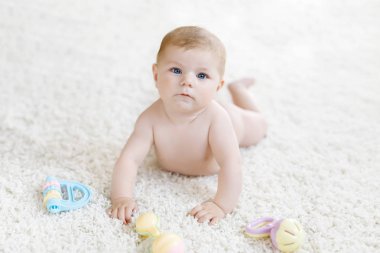 Renkli pastel antika çıngıraklı oyuncakla oynayan şirin bir bebek. Yeni doğmuş bir çocuk, küçük bir kız kameraya bakıyor ve emekliyor. Aile, yeni hayat, çocukluk, başlangıç konsepti. Bebek yakalama.