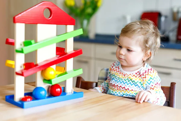 Adorável bonito linda menina brincando com brinquedos educativos em casa ou berçário. Criança saudável feliz se divertindo com pista de bola de brinquedo de madeira colorida. Kid aprendendo a segurar e rolar bola . — Fotografia de Stock