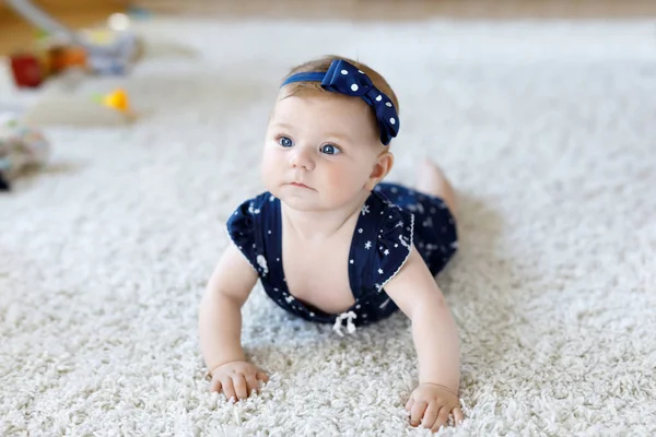 Linda menina adorável em roupas azuis e headband. Criança a olhar para a câmara e a rastejar. Bebê aprendendo agarrar no fundo branco. Retrato da filha feliz. Roupas de moda bebê . — Fotografia de Stock