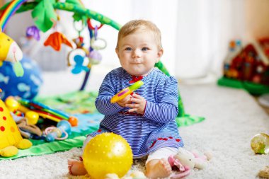 Bebek kız kreş eğitici oyuncaklar ile oynama. Renkli yumuşak oyuncaklar ile eğleniyor mutlu sevimli sağlıklı çocuk. Alıcı topu atma gibi farklı becerileri öğrenme yürümeye başlayan çocuk.