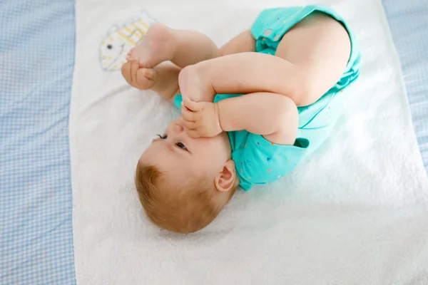 Söt baby med fötter i mun. Bedårande liten flicka sugande fot. — Stockfoto