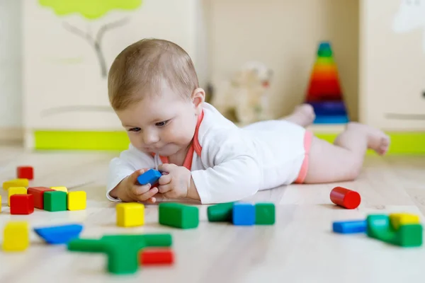 Lindo bebé sonriente feliz jugando con juguetes de sonajero de colores. Niño recién nacido, niña aprendiendo a gatear. Familia, nueva vida, infancia, concepto inicial. Bebé aprendizaje agarrar bloques de madera . — Foto de Stock