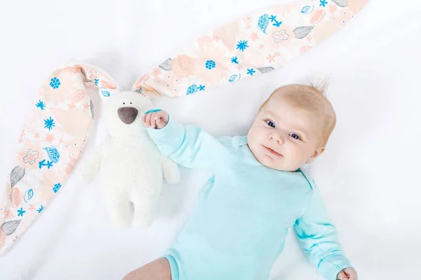Κοντινό πλάνο του αξιολάτρευτο χαριτωμένο νεογέννητο κοριτσάκι των δύο μηνών σε λευκό φόντο. Υπέροχο παιδί που παίζει με βελούδινα κουνελάκια με μακριά αυτιά. Διακοπές, Πάσχα, παιδική ηλικία έννοια — Φωτογραφία Αρχείου