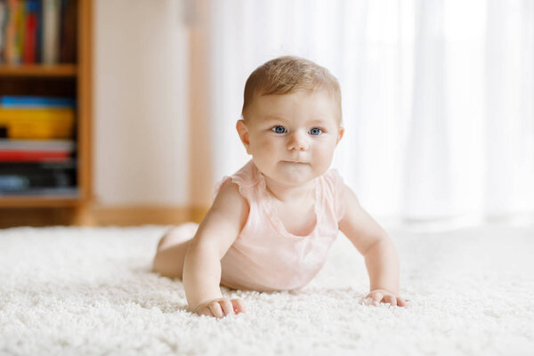 Little funny baby girl lifting body and learning to crawl.