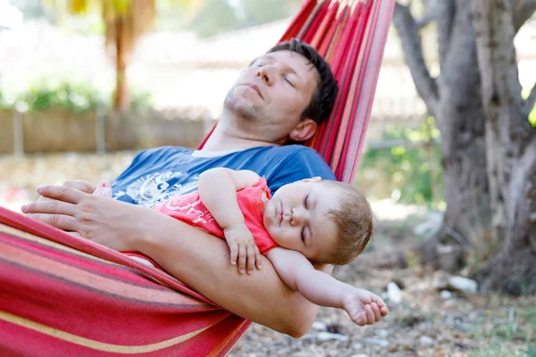 可爱可爱的6月的女婴和她的父亲睡在吊床在室外花园和平。特写的美丽的孩子, 小新生的孩子睡觉。疲倦的爸爸, 男人在床上与女儿 — 图库照片