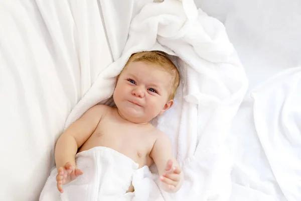 Cute little baby playing with own feet after taking bath. Adorable beautiful girl wrapped in white towels. Crying tired healthy baby — Stock Photo, Image