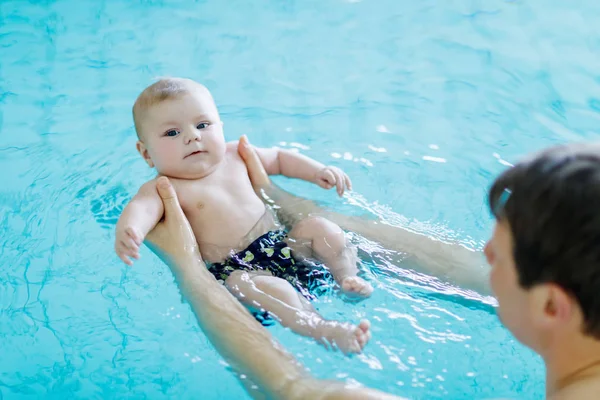 Gelukkig middelbare leeftijd vader met schattige schattige baby in het zwembad zwemmen. Lachende vader en kleine kind, pasgeboren girl plezier samen. Actieve familie besteding van vrije tijd en tijd in het spahotel — Stockfoto