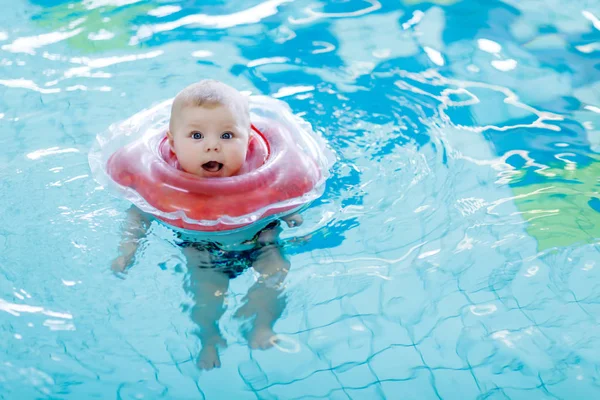 Niedliche kleine Baby-Kind lernen, mit Schwimmring in einem Hallenbad schwimmen. neugeborene Mädchen oder Jungen haben Spaß im Wasser. Aktive gesunde Freizeit und Sport für Babys und Kinder. — Stockfoto