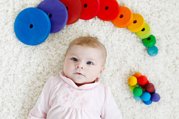 白い背景にカラフルな木製のラトルのおもちゃのボールで遊んでかわいい愛らしい新生児。新しい生まれの子供、女の子は、カメラを見て。家族、新しい生活、子供時代、概念の始まり. — ストック写真