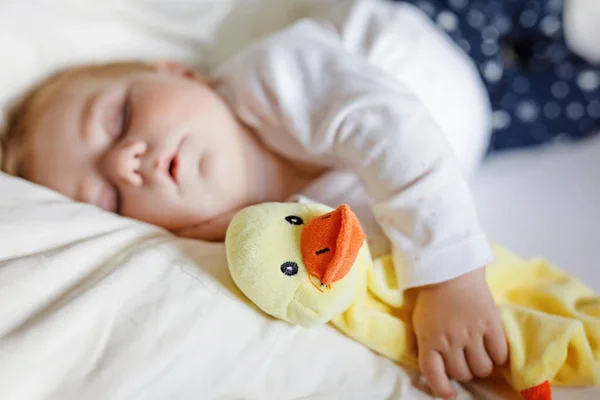 Cute adorable baby girl of 6 months sleeping peaceful in bed at home. Closeup of beautiful calm child, little newborn kid sleeping with plush toy duck. — Stock Photo, Image