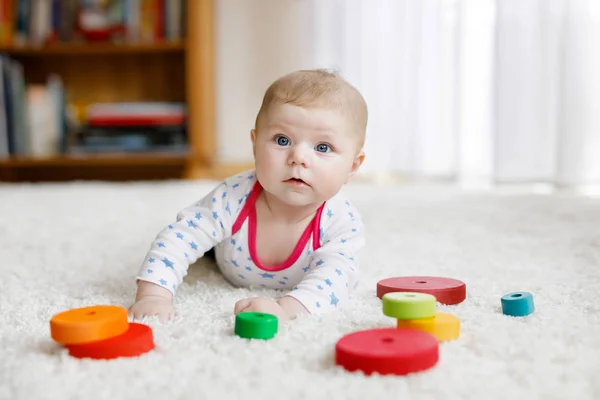 Aranyos aranyos újszülött baba játszik színes fa csörgő játék labda fehér háttér. Újszülött gyerek, a kislány a kamerába néz. Család, új élet, gyermekkor, kezdőfogalom. — Stock Fotó