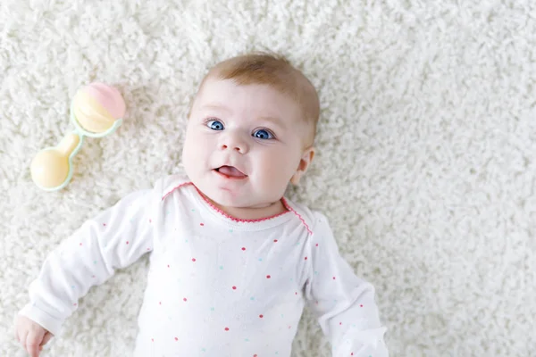 Söt bedårande nyfödda barnet leker med färgglada pastellfärger vintage skallra leksak. Nyfödda barnets, lilla flickan tittar på kameran. Familj, nytt liv, barndom, början koncept. Baby lärande grab. — Stockfoto