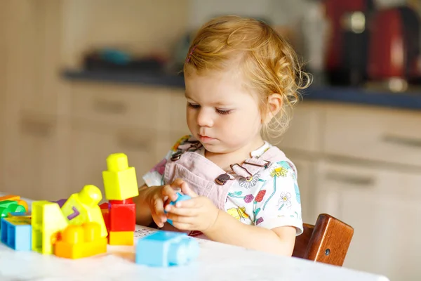 Bebek odasında eğitici oyuncaklarla oynayan tatlı bir kız. Mutlu sağlıklı çocuk evde renkli farklı plastik bloklarla eğleniyor. Sevimli bebek öğrenimi yaratma ve inşa etme. — Stok fotoğraf