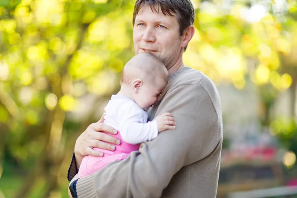 Close-up of tired young father with crying baby girl. Dad with daughter outdoors, love. Tiny child crying. Bonding, family, new life. — Stock Photo, Image