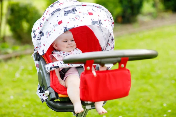 Schattig klein mooie babymeisje van 6 maanden achterover in de kinderwagen of wandelwagen en moeder wachten. Gelukkig lachend kind met blauwe ogen.. — Stockfoto