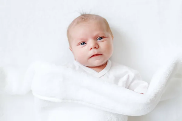 Χαριτωμένο αξιολάτρευτο νεογέννητο μωρό σε λευκό κρεβάτι και τυλιγμένο σε κουβέρτα. Νεογέννητο παιδί, μικρό κορίτσι που κοιτάζει έκπληκτο με την κάμερα. Οικογένεια, νέα ζωή, παιδική ηλικία, έννοια έναρξης — Φωτογραφία Αρχείου