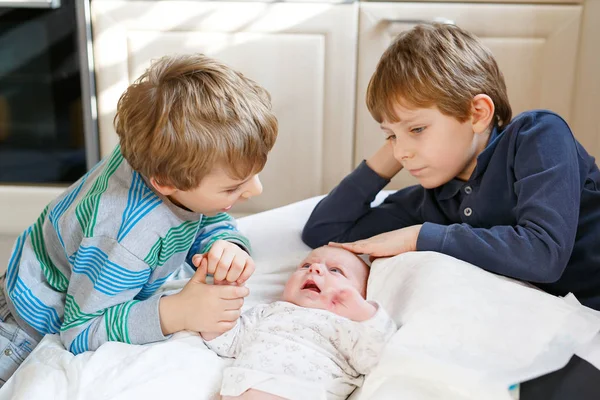 Two little kids boys with newborn baby girl, cute sister. Siblings. Brothers and baby playing with colorful toys and rattles together. Kids bonding. Family of three bonding, love — Stock Photo, Image